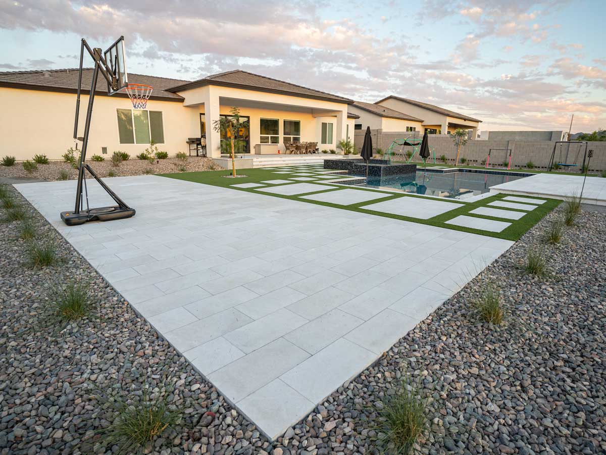 Large-format paver patio with turf inlay and basketball hoop beside pool, Queen Creek AZ
