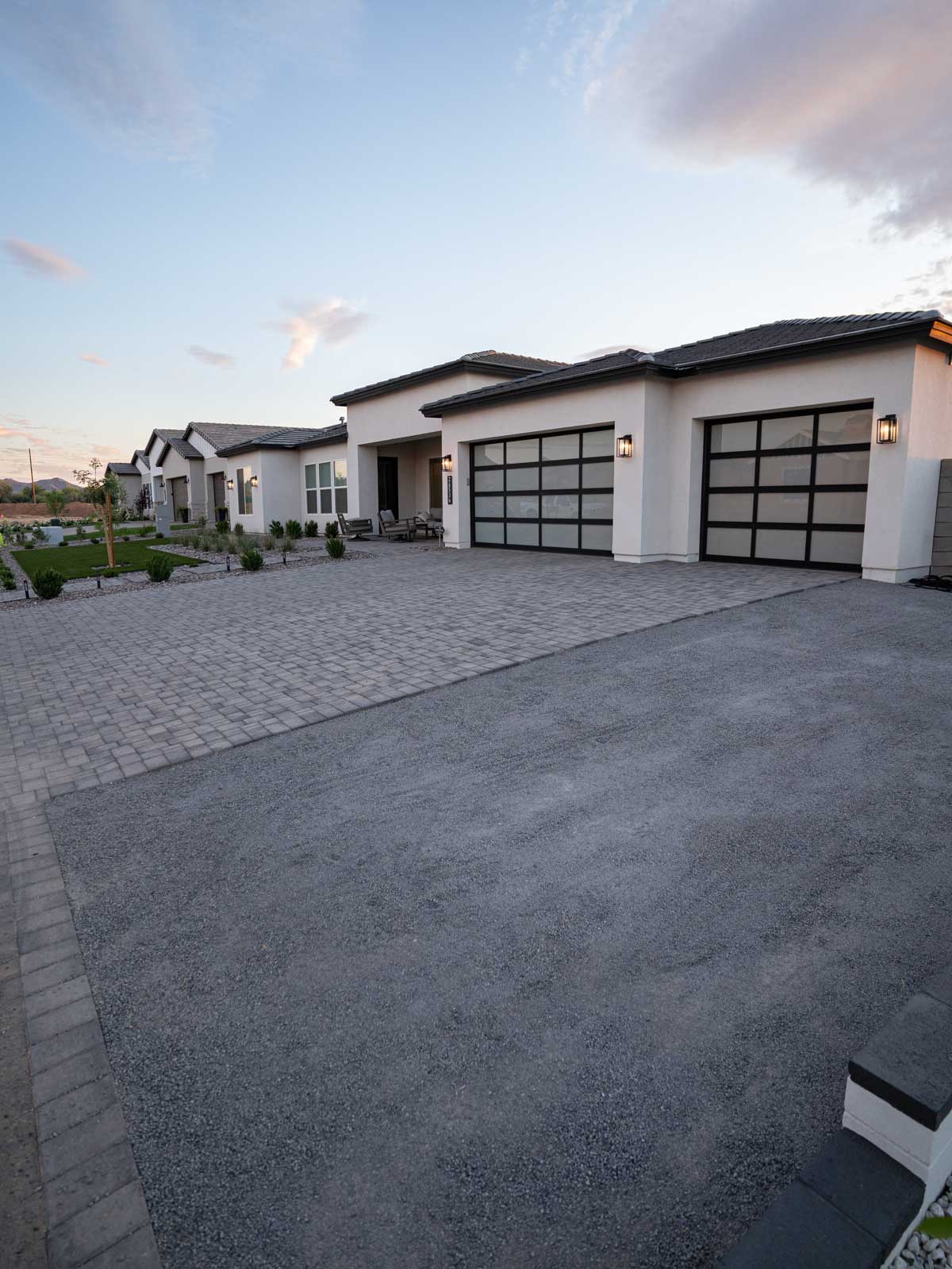 Modern paver driveway and front yard turf at stucco home with glass garage doors, Queen Creek