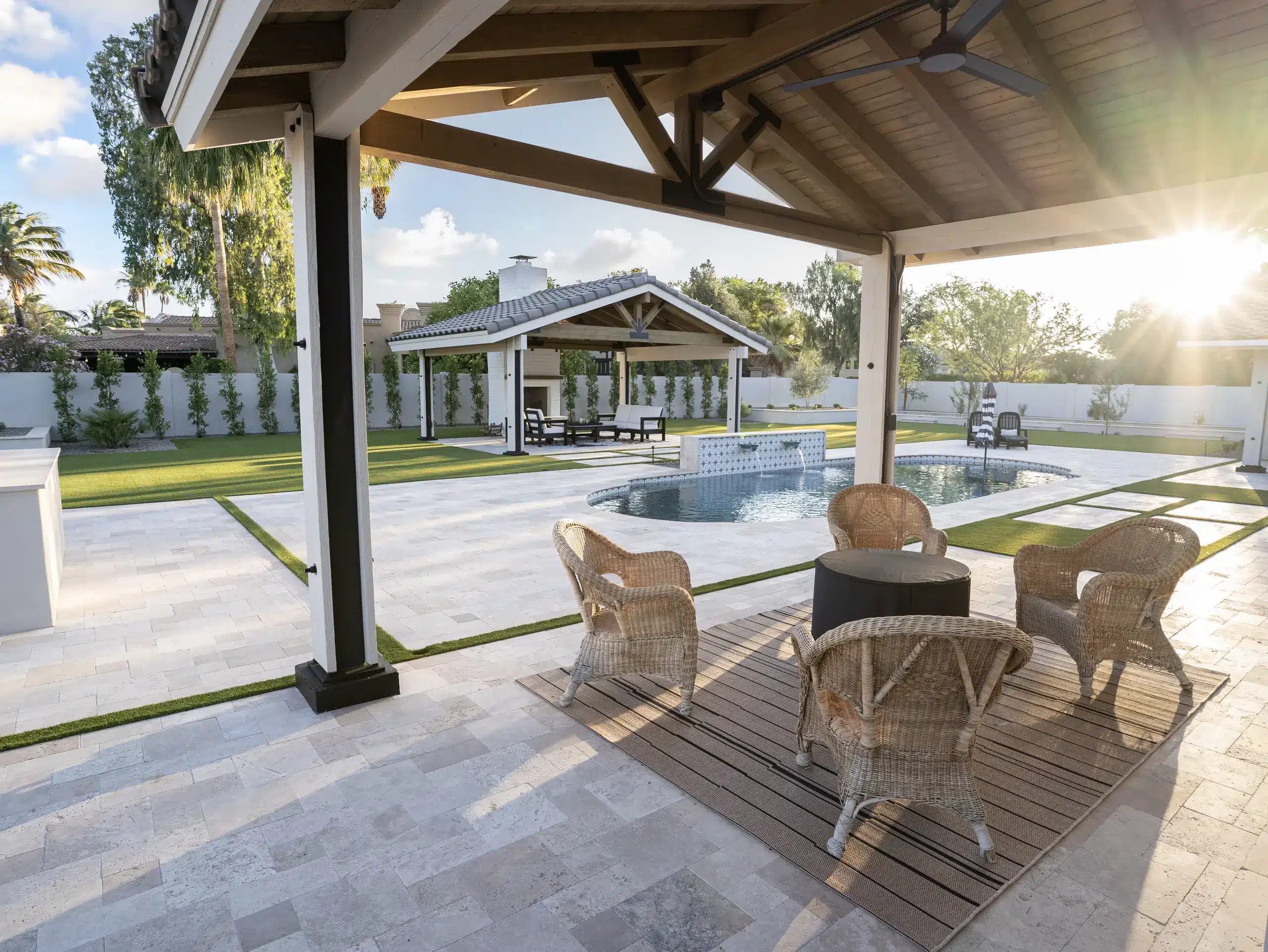 Covered patio seating area looking out over artificial turf, paver hardscape and a poolside ramada in a Scottsdale backyard